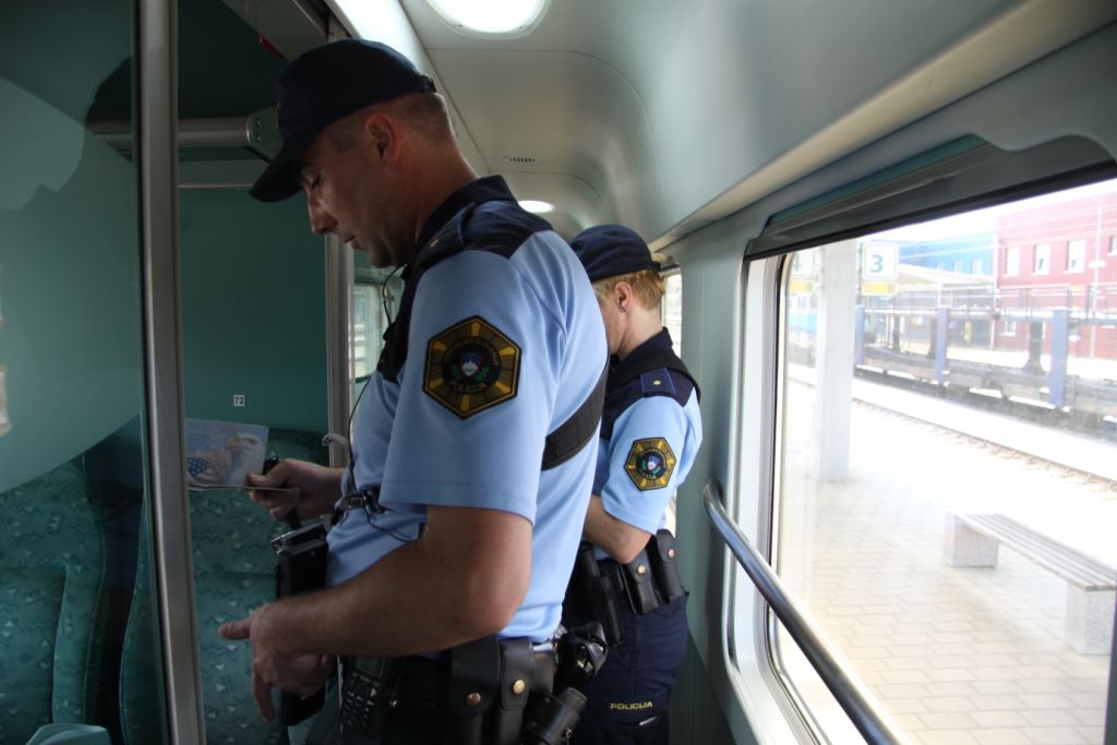 slika dveh policistov, ki pregledujeta osebne dokumente na vlaku