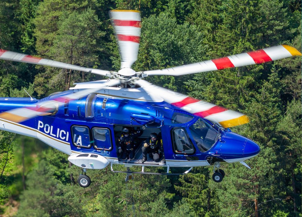 Simbolična fotografija policijskega helikopterja, ki leti nad drevesi.