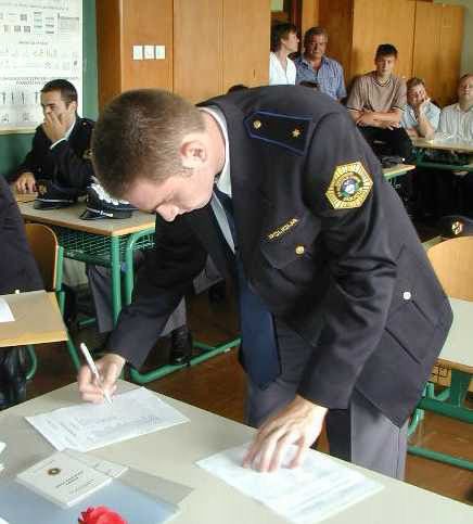 slika policista, ki podpisuje odločbo o sklenjenem delovnem razmerju