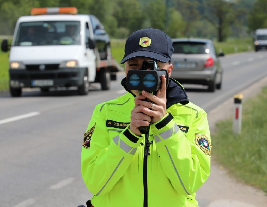 Prometna policistka meri hitrost, gleda skozi ročni merilnik