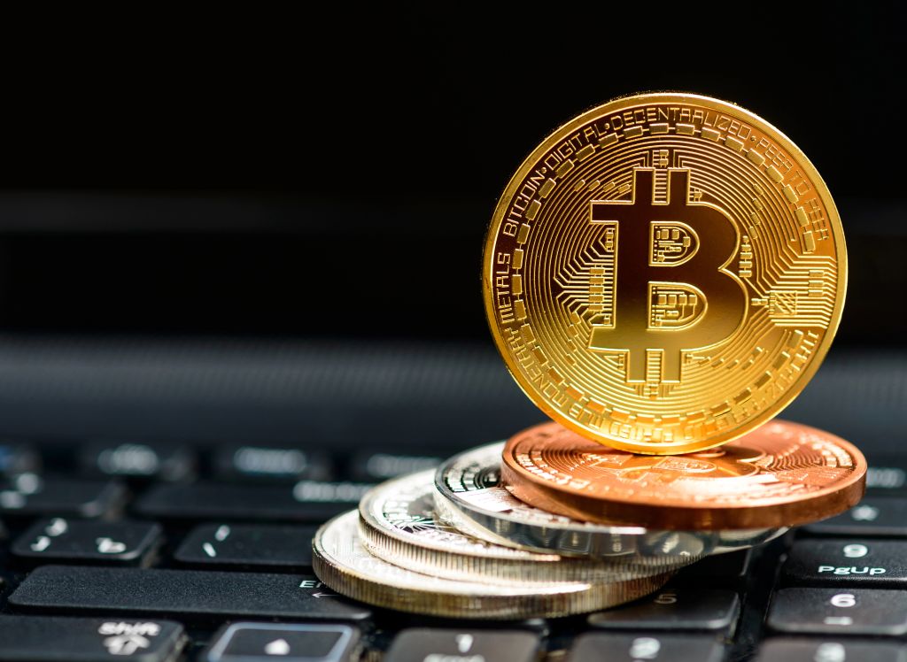 Nekaj kovancev - bitcoinov, postavljenih na računalniško tipkovnico (simbolična slika)
