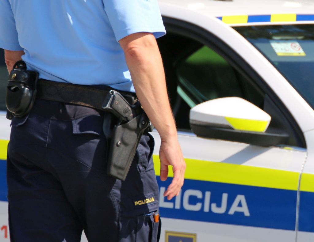 Policist se približuje policijskemu vozilu