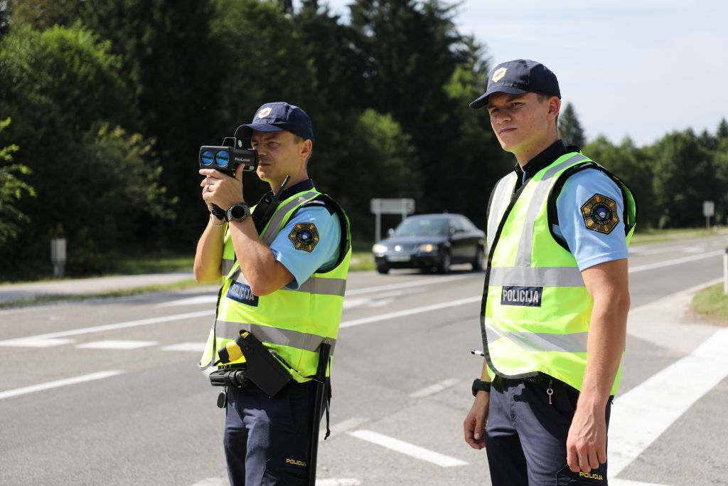 Policista merita hitrost ob cesti z radarjem.