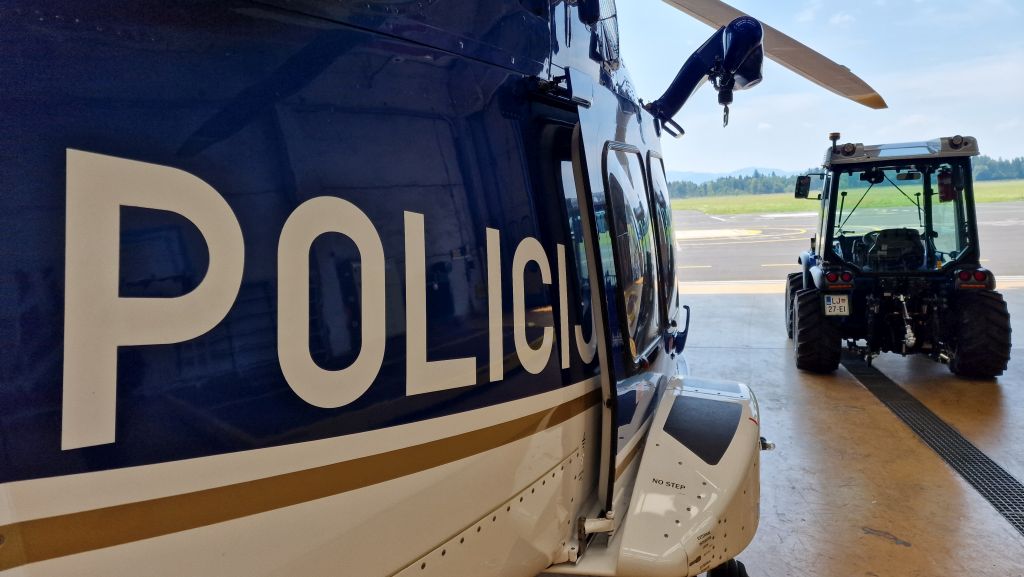 Fotografija prikazuje pogled od zadaj na traktor, ki gre iz hangarja.