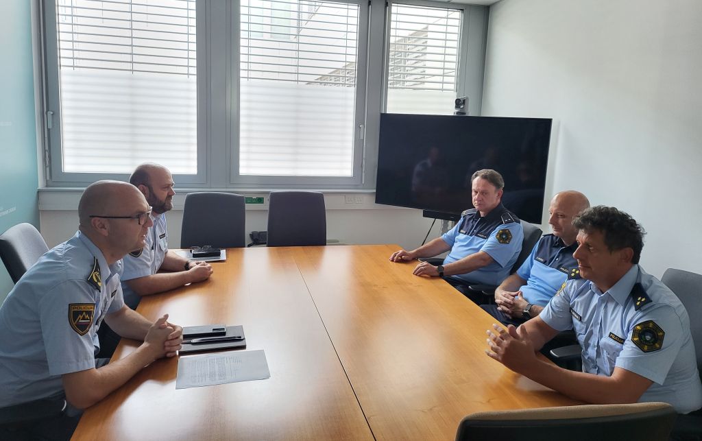 Na fotografiji sprejeti policisti sedijo za veliko mizo in se pogovarjajo s pomočnikom generalnega direktorja policije in sodelavcem Edom Behlićem iz Sektorja za mednarodne policijske operacije..