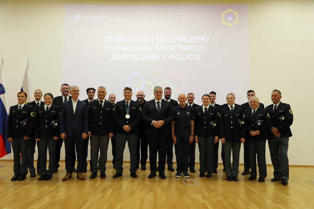 Skupinska fotografija, na kateri pred steno stojijo olimpijci, policisti in vodstvo MNZ ter Policije