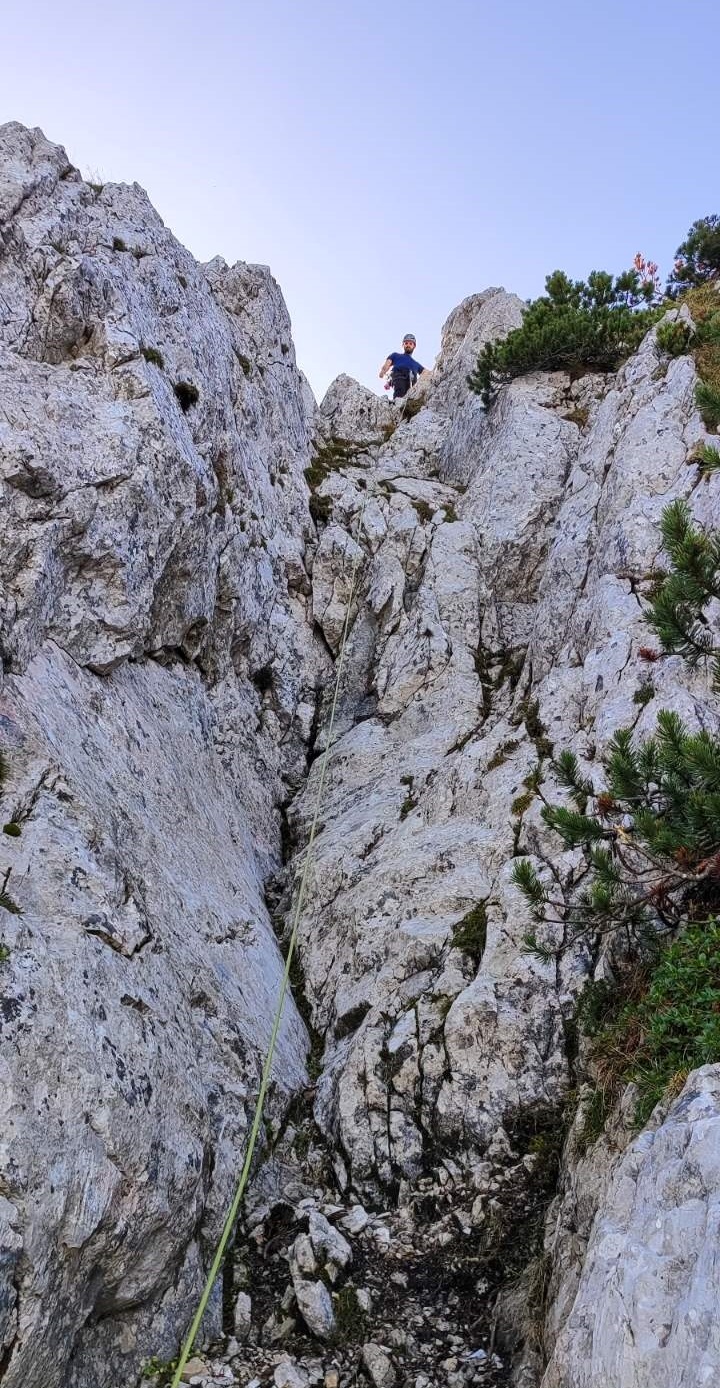Mesto na grebenu, kjer se je odlomila skala. Z vrha grebena, kjer stoji policist, se plezalna vrv spušča v globino