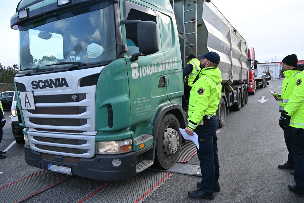 Štirje prometni policisti stojijo ob kabini ustavljenega tovornjaka, poteka kontrola voznika in vozila