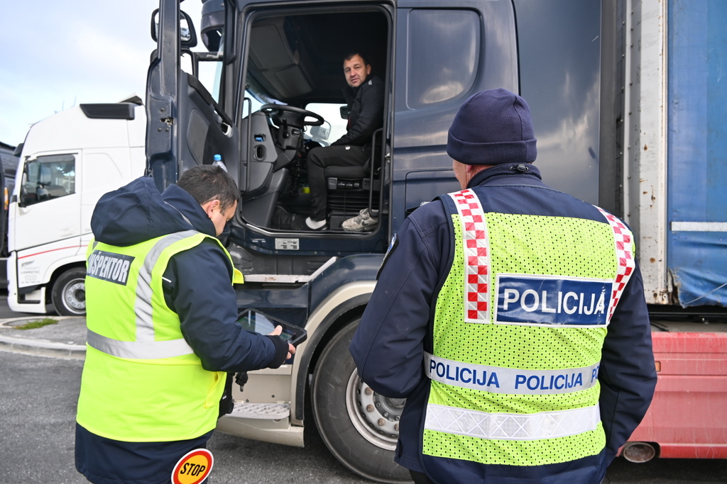 Prometna policista med kontrolo voznika tovornjaka, slednji sedi v kabini, policista stojita ob vozilu