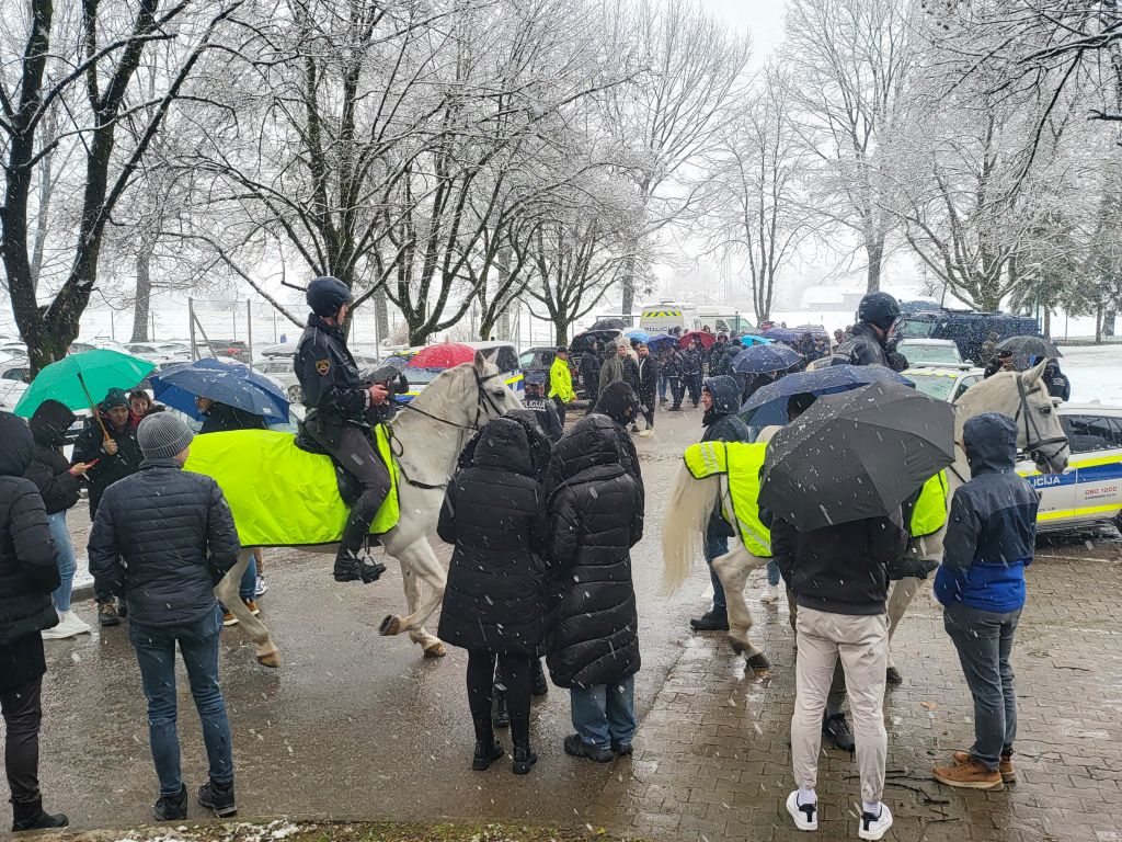 Množica obiskovalcev čaka na ploščadi pred akademijo, poleg sta tudi policista konjenika.