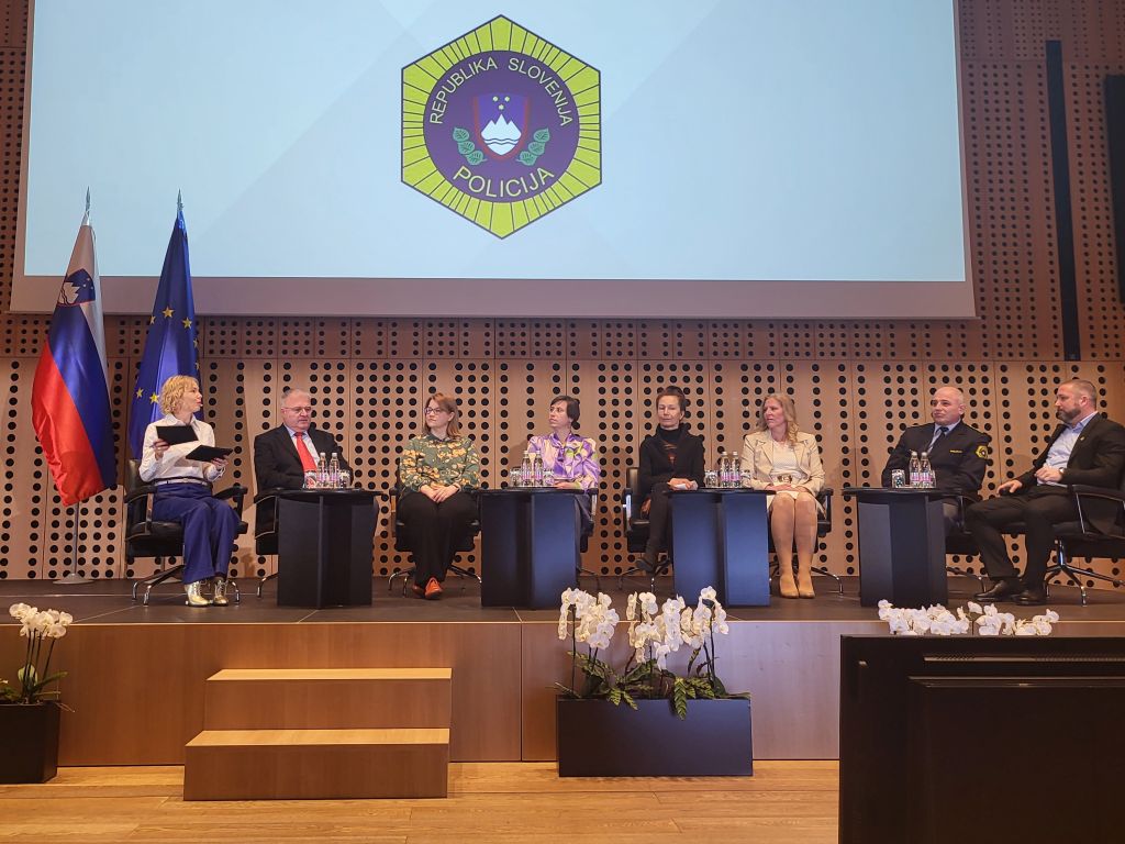Udeleženci današnjega posveta, sedem govorcev je, sedijo na odru, skrajno levo moderatorka.