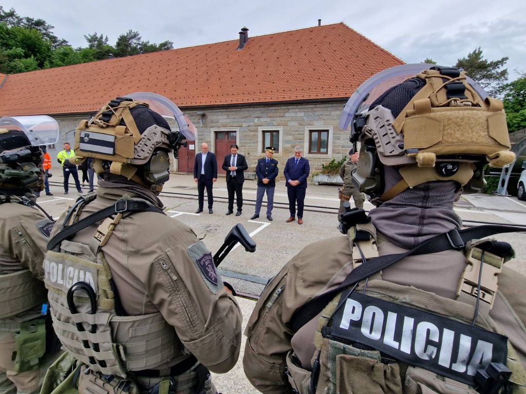 V ozadju: predstavniki vodstva HSE, MNZ in Policije stojijo zunaj, med nagovorom sodelujočim na vaji, v ospredju pripadniki Specialne enote, obrnjeni so proti govorcem.