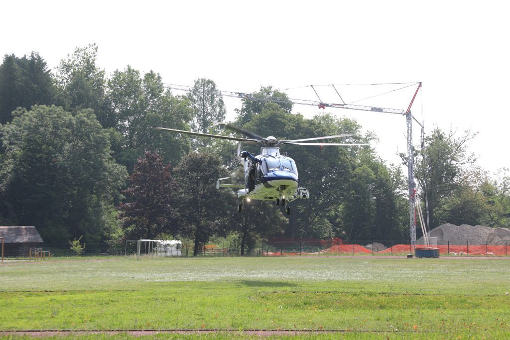Policijski helikopter lebdi nekaj metrov nad tlemi (nad travnikom Policijske akademije).