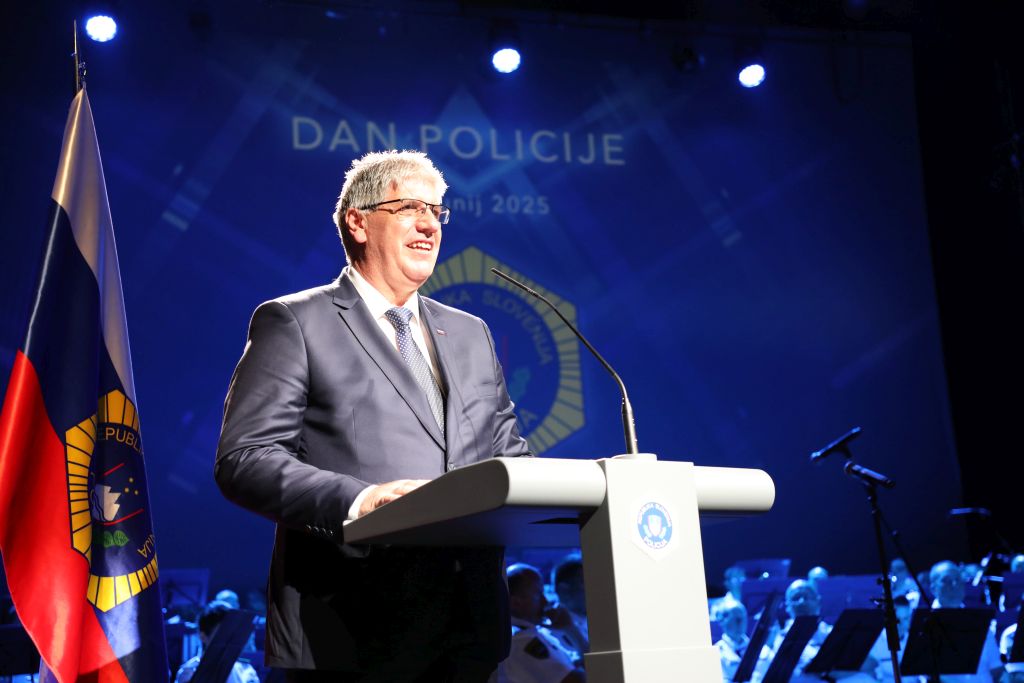 Minister Poklukar med nagovorom, stoji za govornico na odru, pred sabo ima mikrofon.