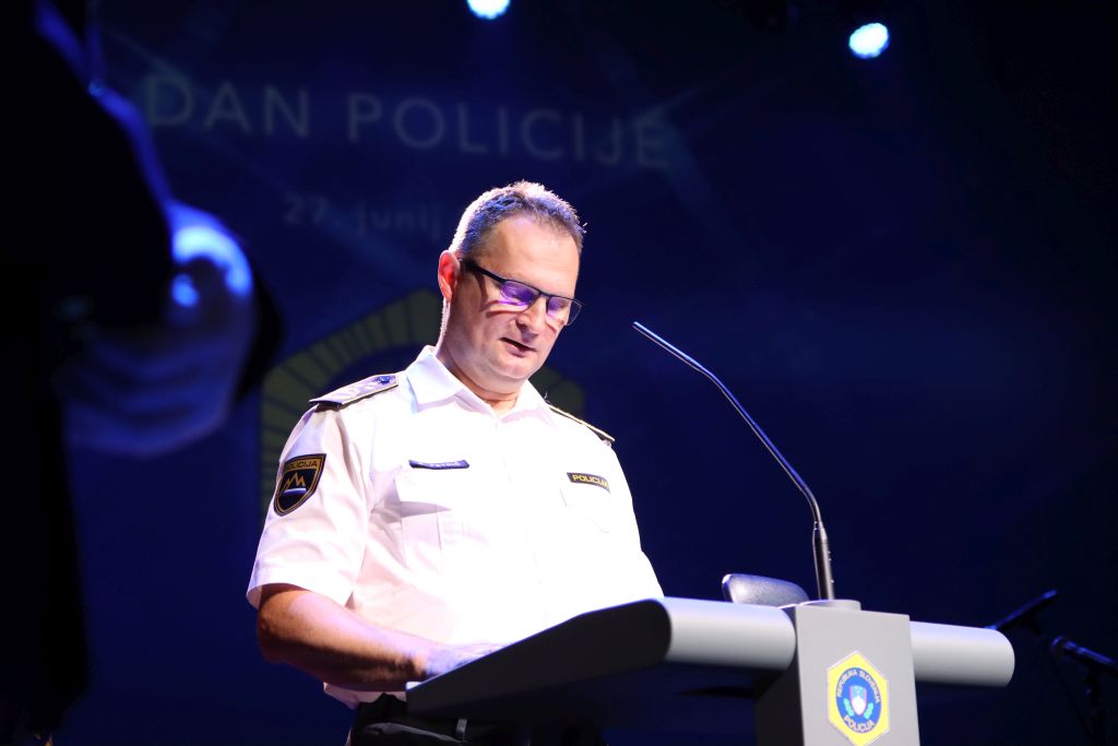 Damjan Petrič med nagovorom, stoji za govornico, pred sabo ima mikrofon.