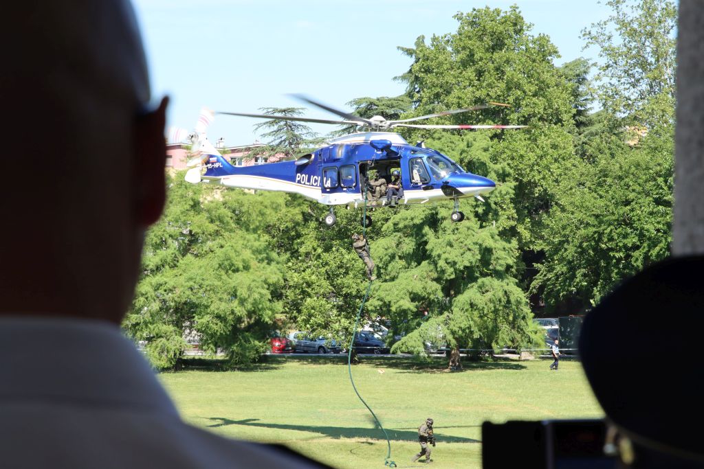 Iz policijskega helikopterja se po vrvi spušča policist Specialne enote na travnik spodaj