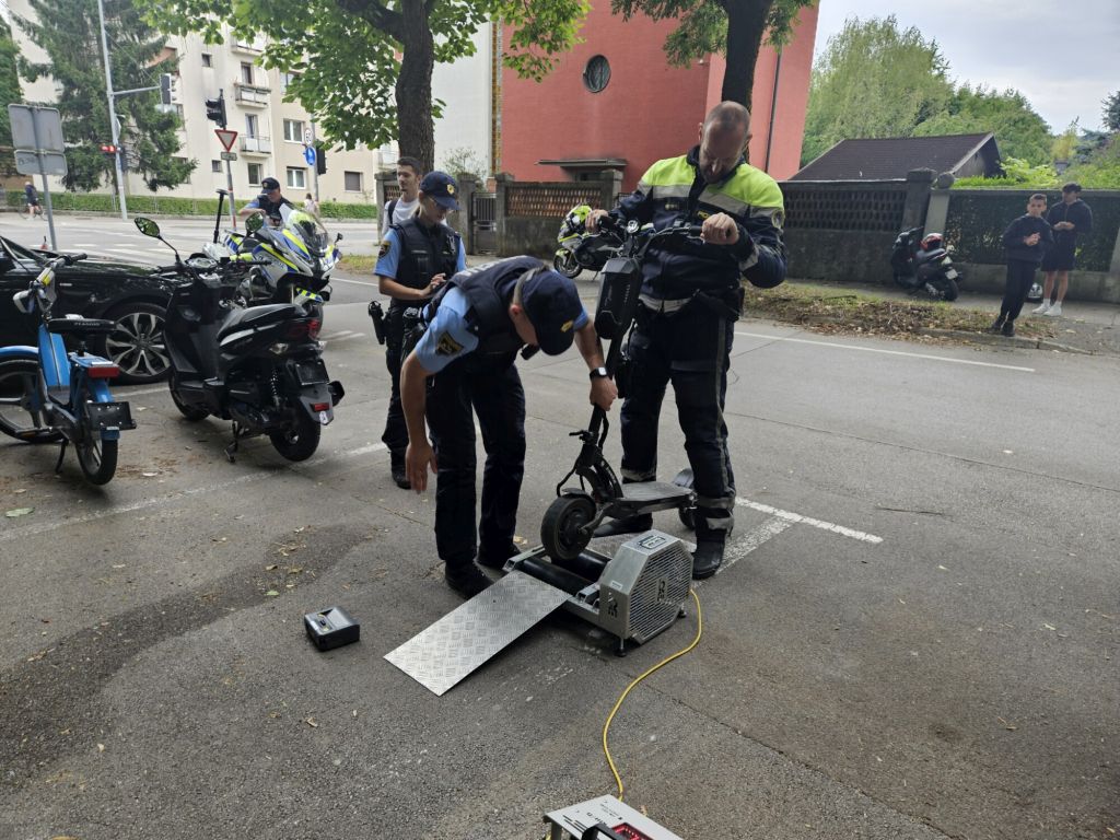 Dva policista med prikazom delovanja naprave za ugotavljanje največje hitrosti, ki jo lahko doseže e-skiro.