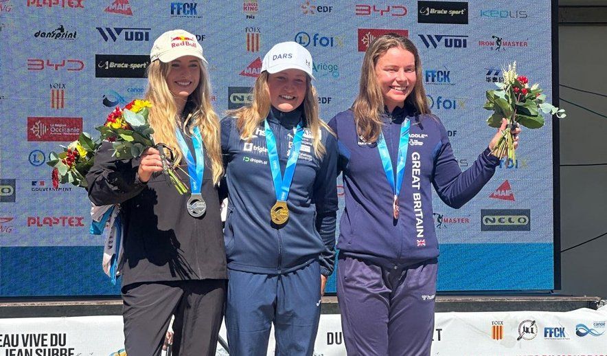 Eva Alina Hočevar stoji na zmagovalnih stopničkah, v sredini, z zlato medaljo okrog vratu