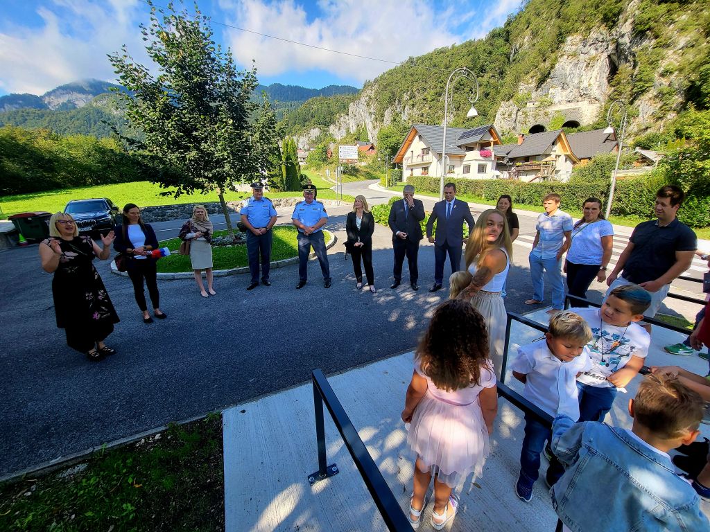 Delegacija policije in ministrstva, učitelji in otroci stojijo pred šolo.
