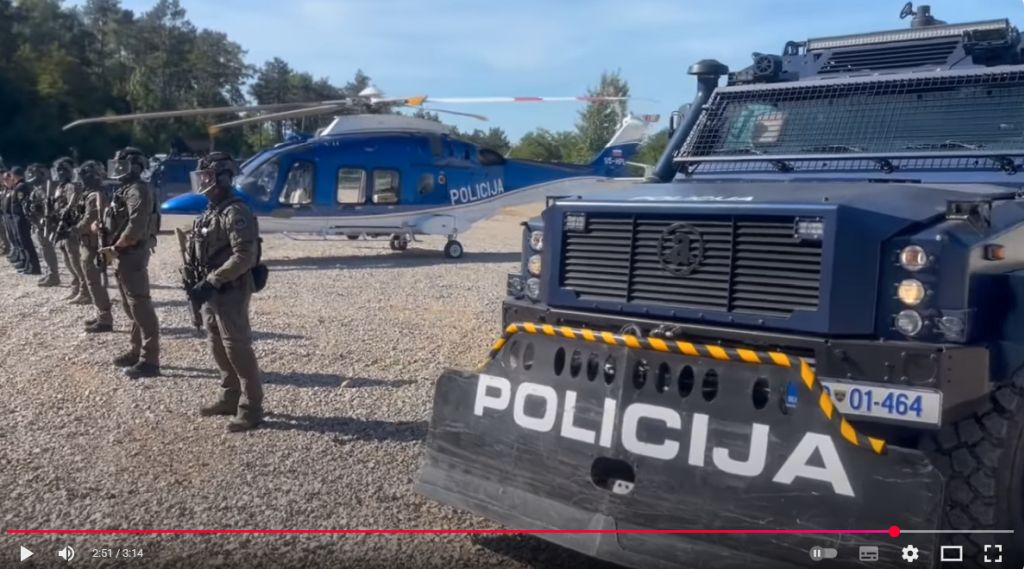 Na poligonu so pripadniki Specialne enote v postroju, v ozadju policijski helikopter (izsek iz videa)