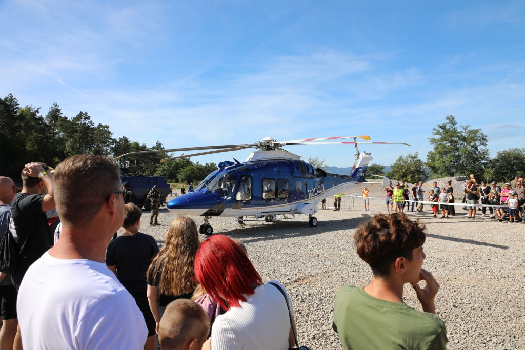 Obiskovalci si ogledujejo policijski helikopter, ki je pristal na poligonu.