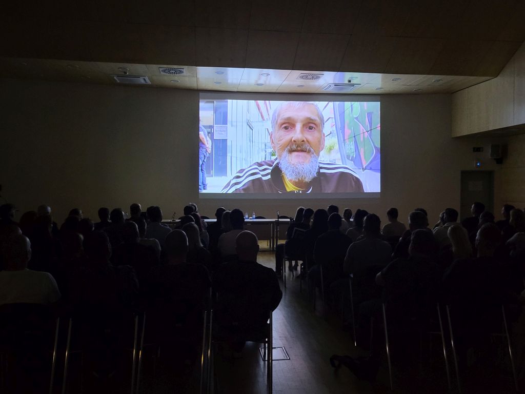 Zatemnjena kongresna dvorana med predvajanjem filma na platnu