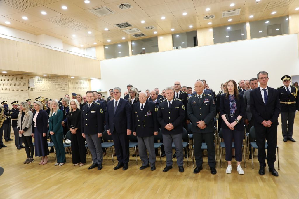Udeleženci v dvorani stojijo na začetku slovesnosti.