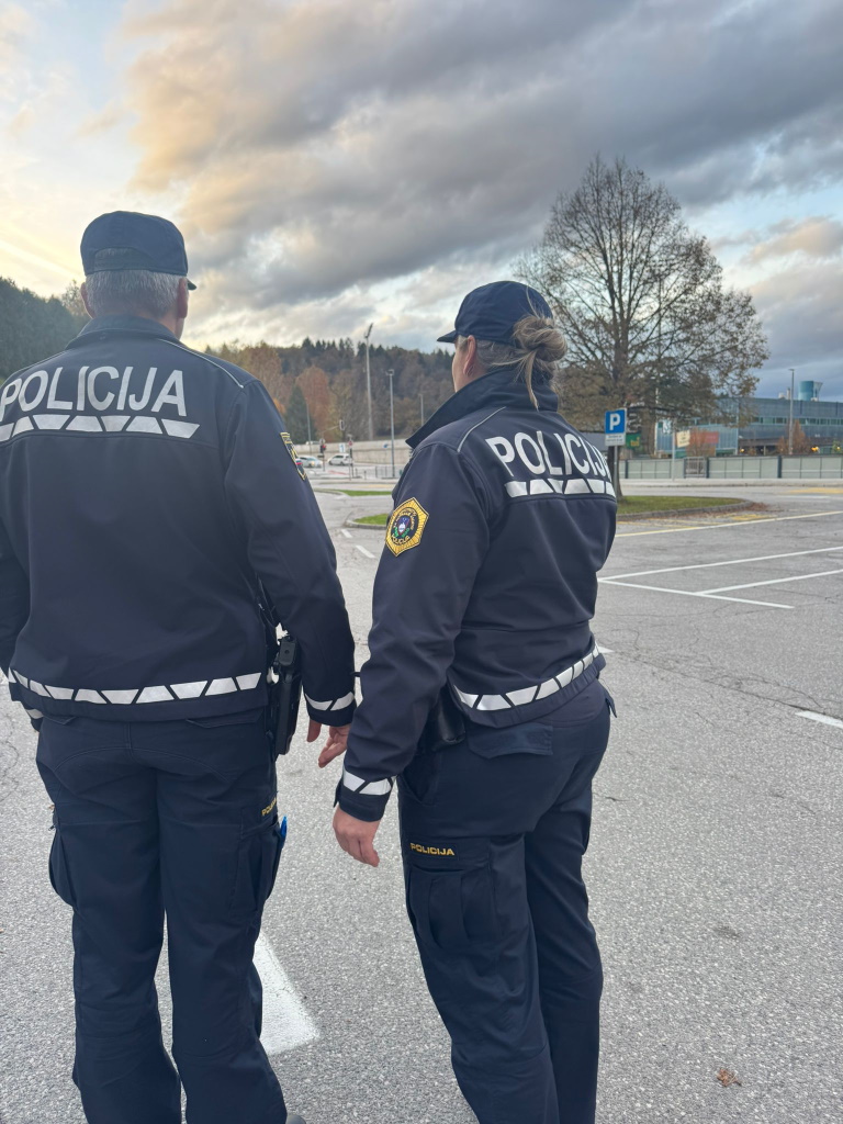 Policist in policistka stojita na parkirišču