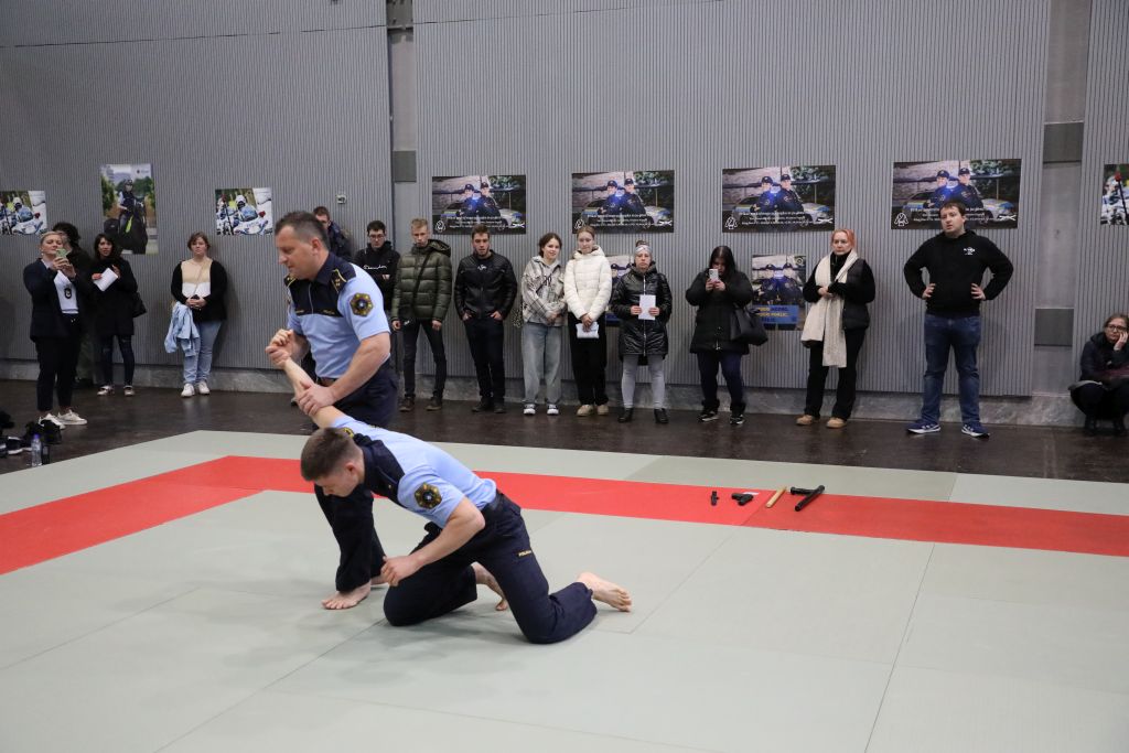 Policista na blazinah kažeta policijski prijem z vzvodom roke.