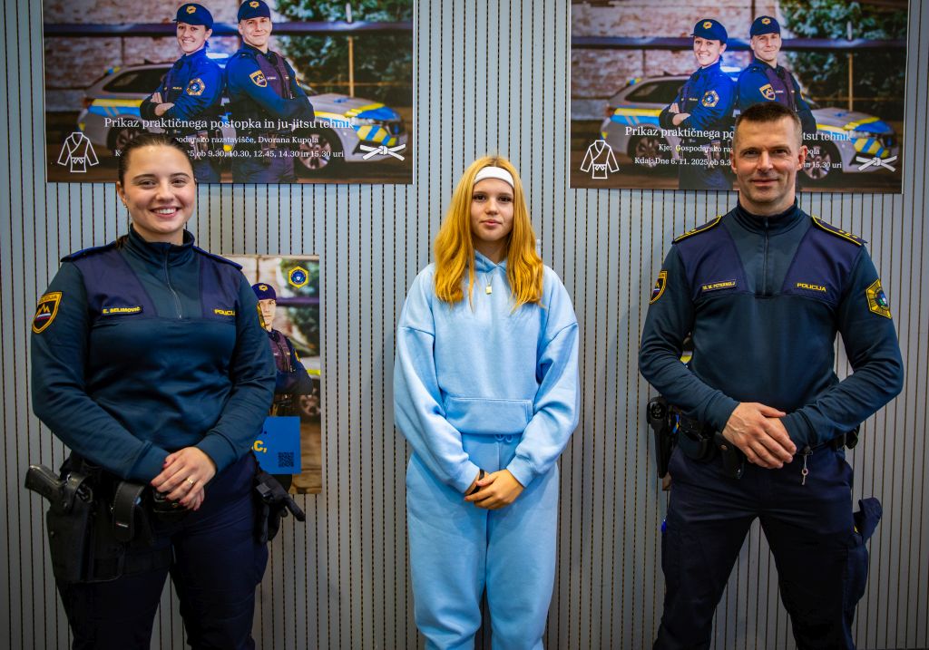 Mlada obiskovalka stoji med dvema policistoma