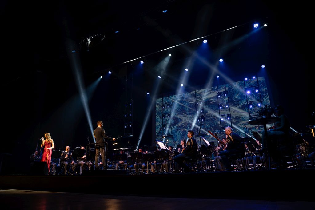 Na odru stoji pevka Monika Avsenik, za njo igra Policijski orkester