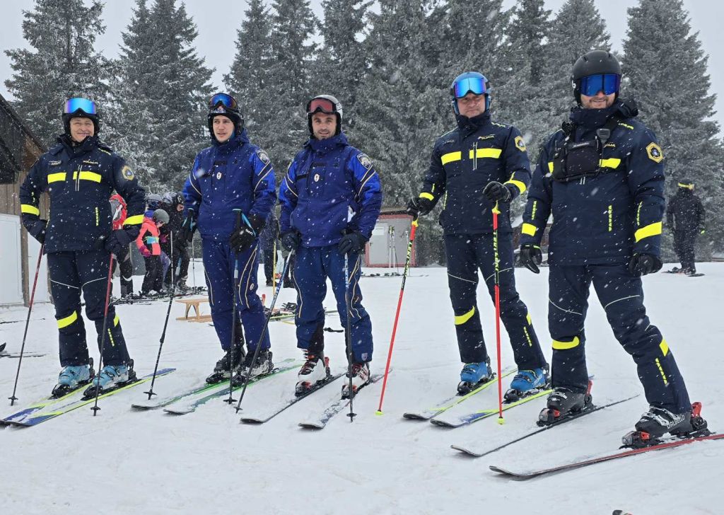 Hrvaška policista smučarja (na sliki drugi in tretji z leve) stojita na smučkah, ob njiju so trije slovenski policisti na smučeh.
