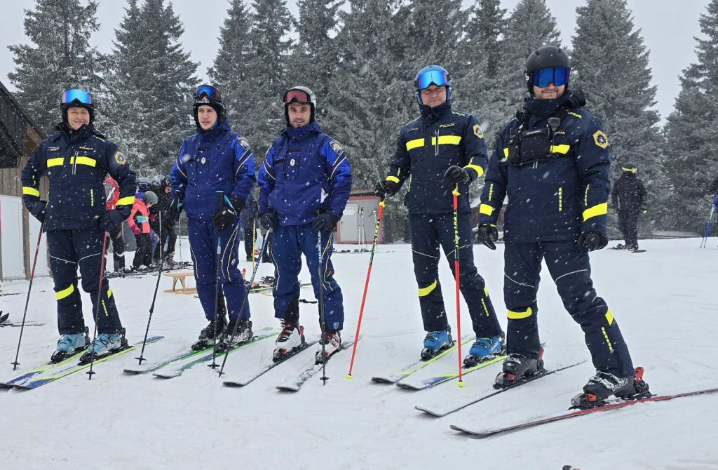 Hrvaška policista smučarja (na sliki drugi in tretji z leve) stojita na smučkah, ob njiju so trije slovenski policisti na smučeh.