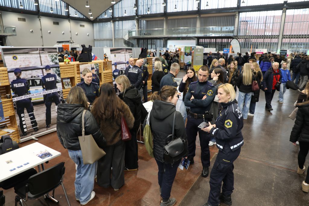 Pogled z višine na sejmišče, v ospredju je razstavni prostor policije. Obiskovalci se pogovarjajo s policisti.