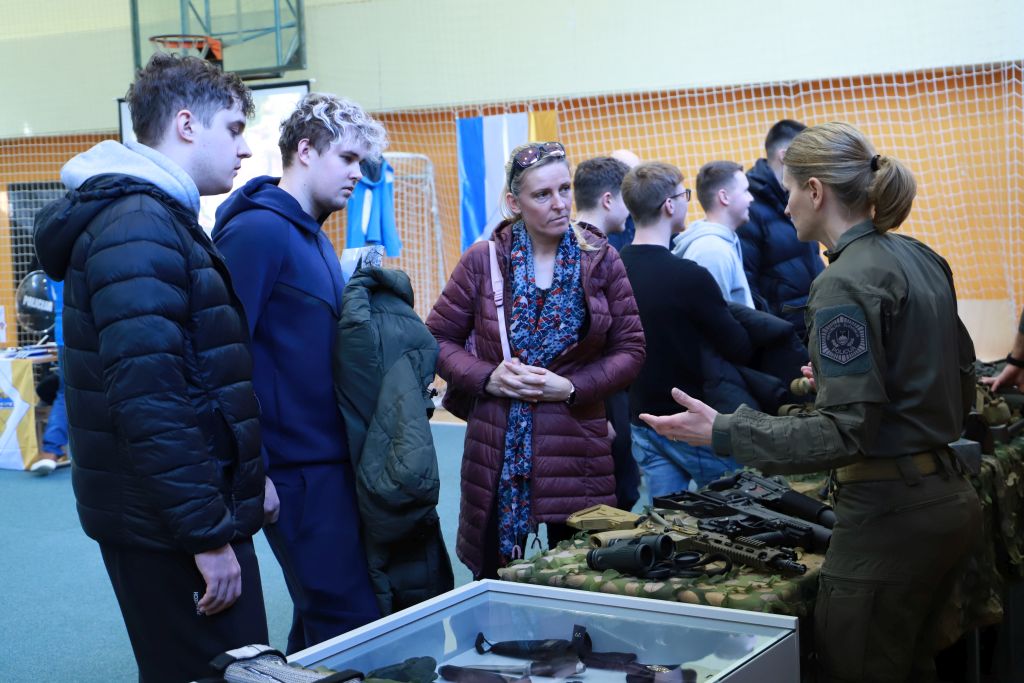 Policistka Specialne enote v pogovoru z dvema obiskovalcema in njunimi starši.