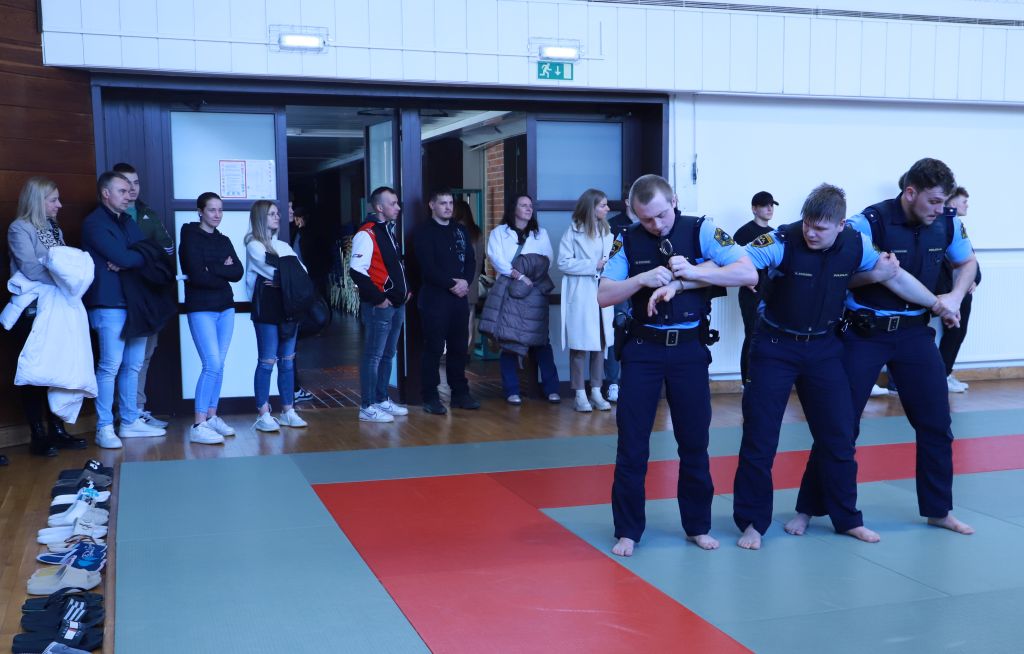 Trije kandidati - študenti VPŠ v borilnici med prikazom, kako obvladati in vkleniti storilca.