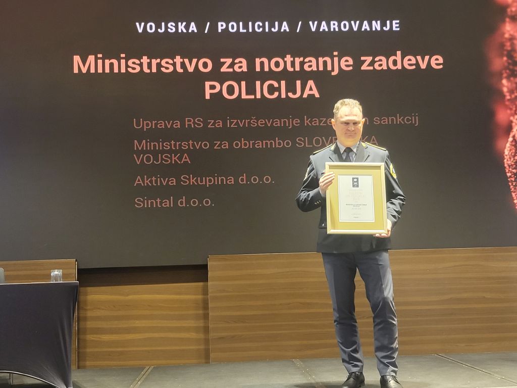 Na odru stoji Damjan Petrič, v rokah drži priznanje