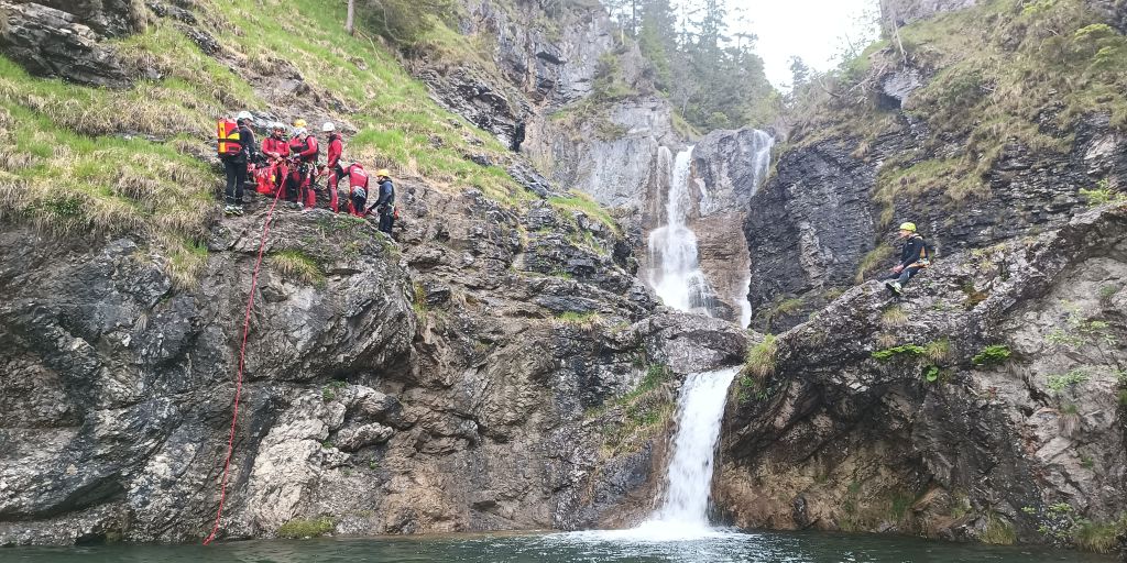 Ekipa reševalcev stoji na strmi skali ob slapu