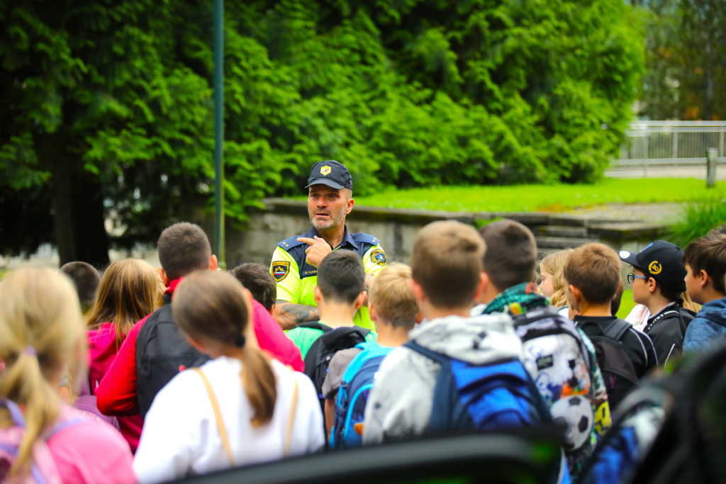 Prometni policist zunaj govori pred skupino otrok.