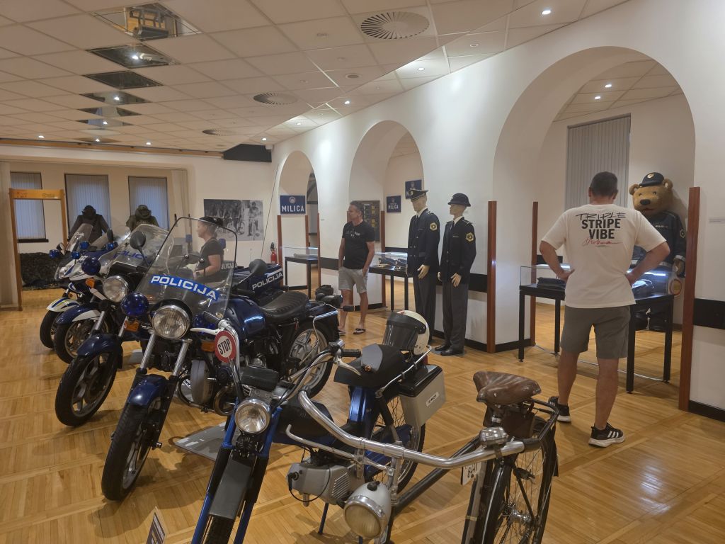 Obiskovalci si ogledujejo muzejska policijska motorna vozila.