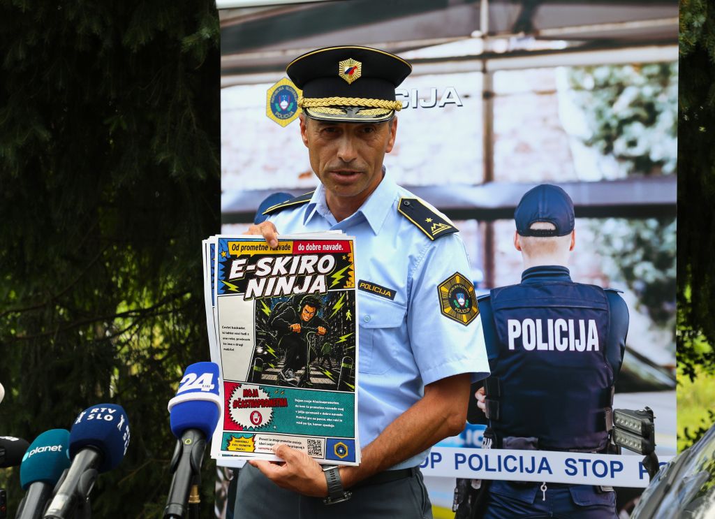Vehovec daje izjavo novinarjem, pred sabo drži enega od plakatov.
