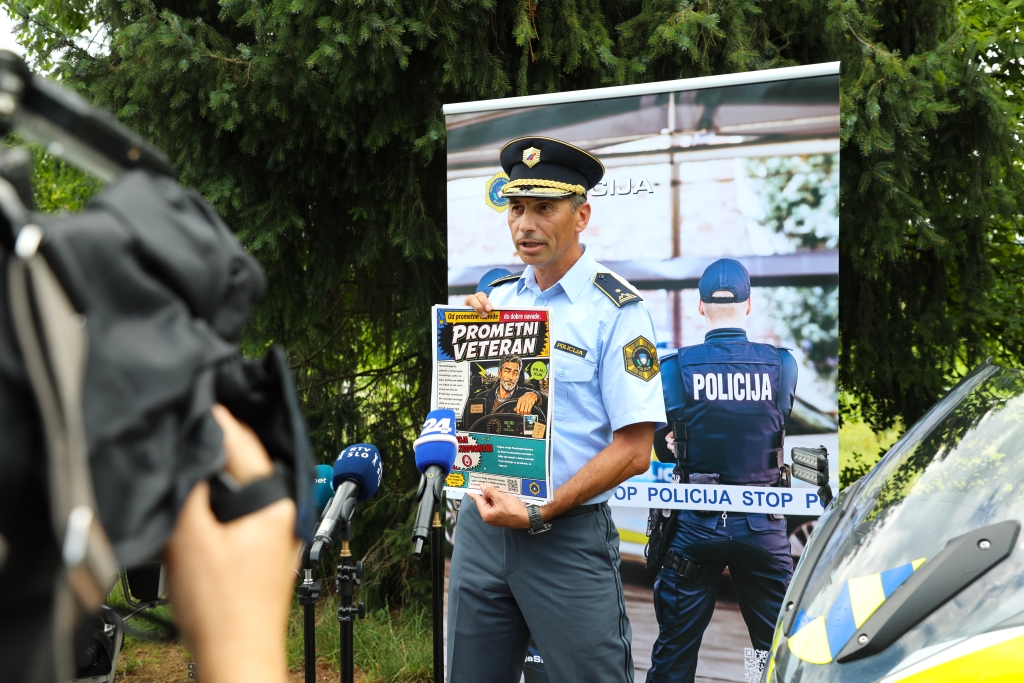 Vehovec daje izjavo novinarjem, pred sabo drži enega od plakatov.
