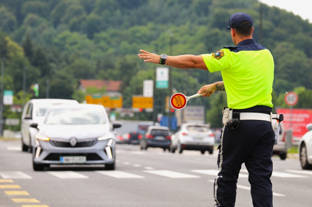 Prometni policist ustavlja vozilo s stop loparčkom.