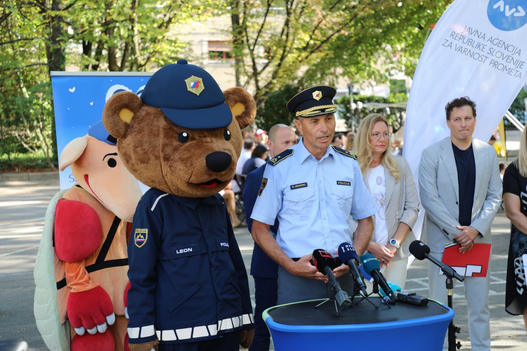 Vehovec med izjavo za javnost (stoji za govornico, ob njem maskota policist Leon)