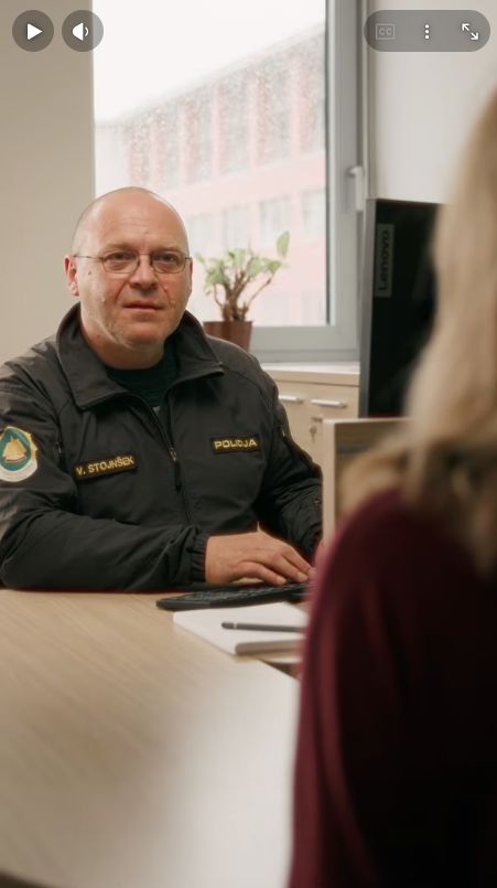 zajem zaslona iz videa: policist na postaji med pogovorom s prijaviteljico