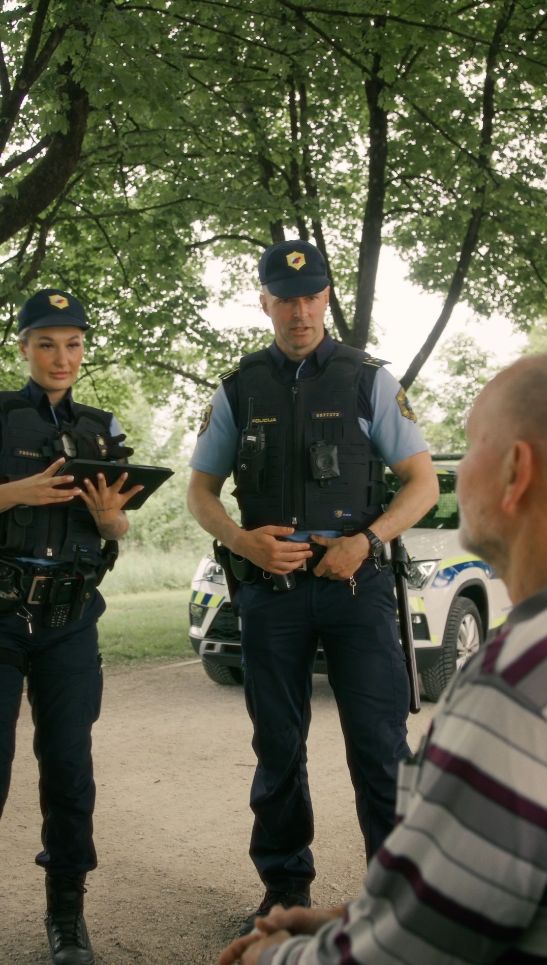 zajem zaslona iz videa: policista se pogovarjata s starejšim moškim, ki sedi na klopci v parku