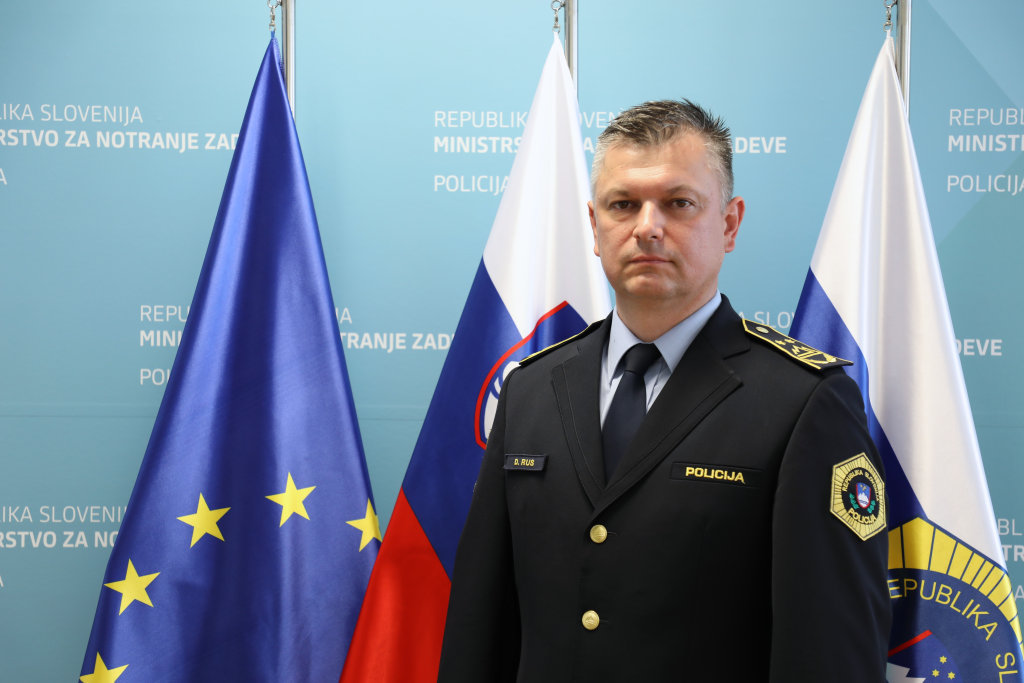 Donald Rus, v ozadju so zastave: evropska, slovenska in policijska.