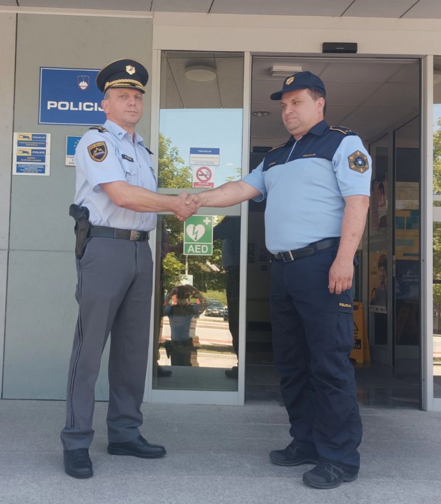 Kolar in Kovač se rokujeta pred vhodom na policijsko postajo.