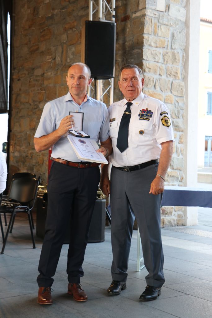 Dejan Grandič in Fabio Steffe stojita, Grandič ima v rokah priznanje.