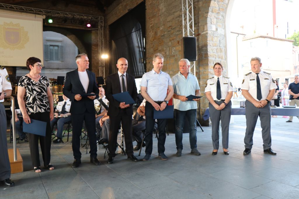Prejemniki zlatega ščita policije stojijo na odru.
